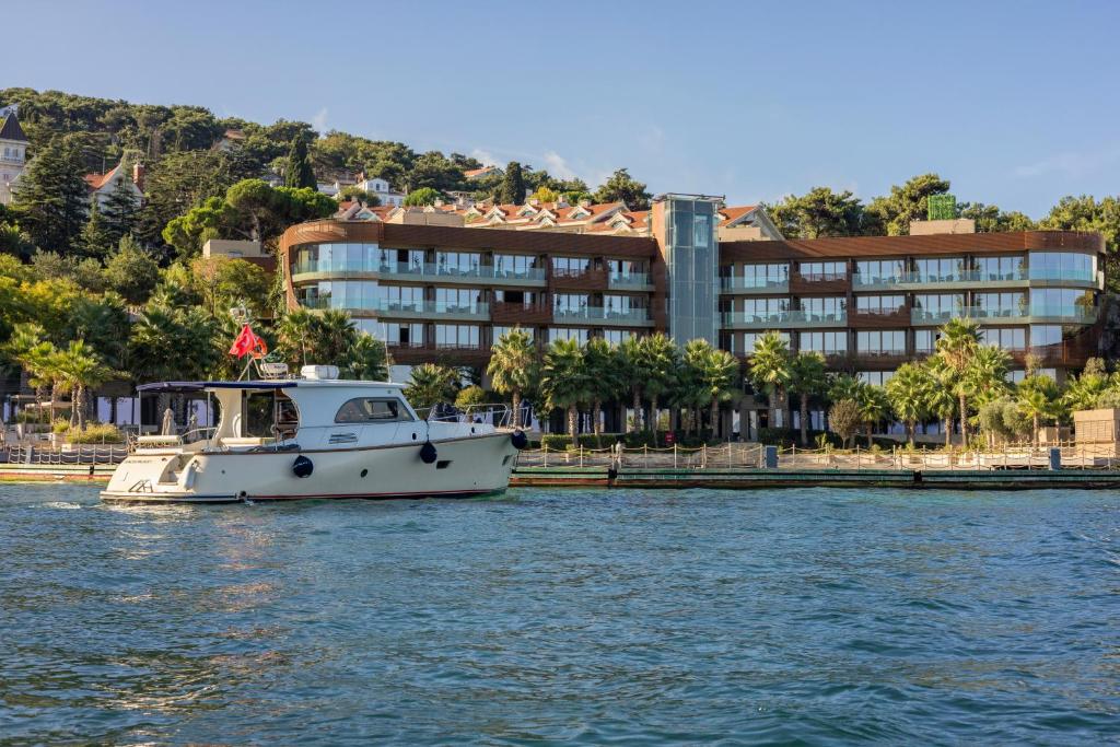 una barca in acqua davanti a un edificio di Princes' Palace Resort, Buyukada - Member of The Leading Hotels of the World a Adalar
