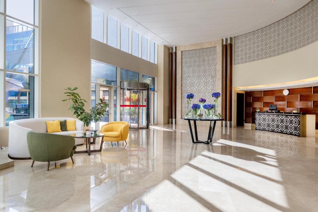 a lobby with a couch and a table and chairs at Grand Millennium Al Wahda Hotel and Executive Apartments Abu Dhabi in Abu Dhabi