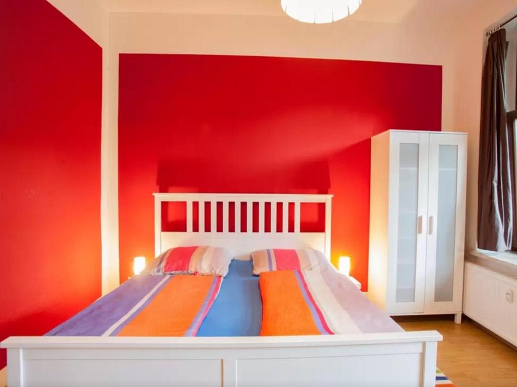 a bedroom with a red wall with a bed at Im Herzen - Zentral in Leipzig in Leipzig