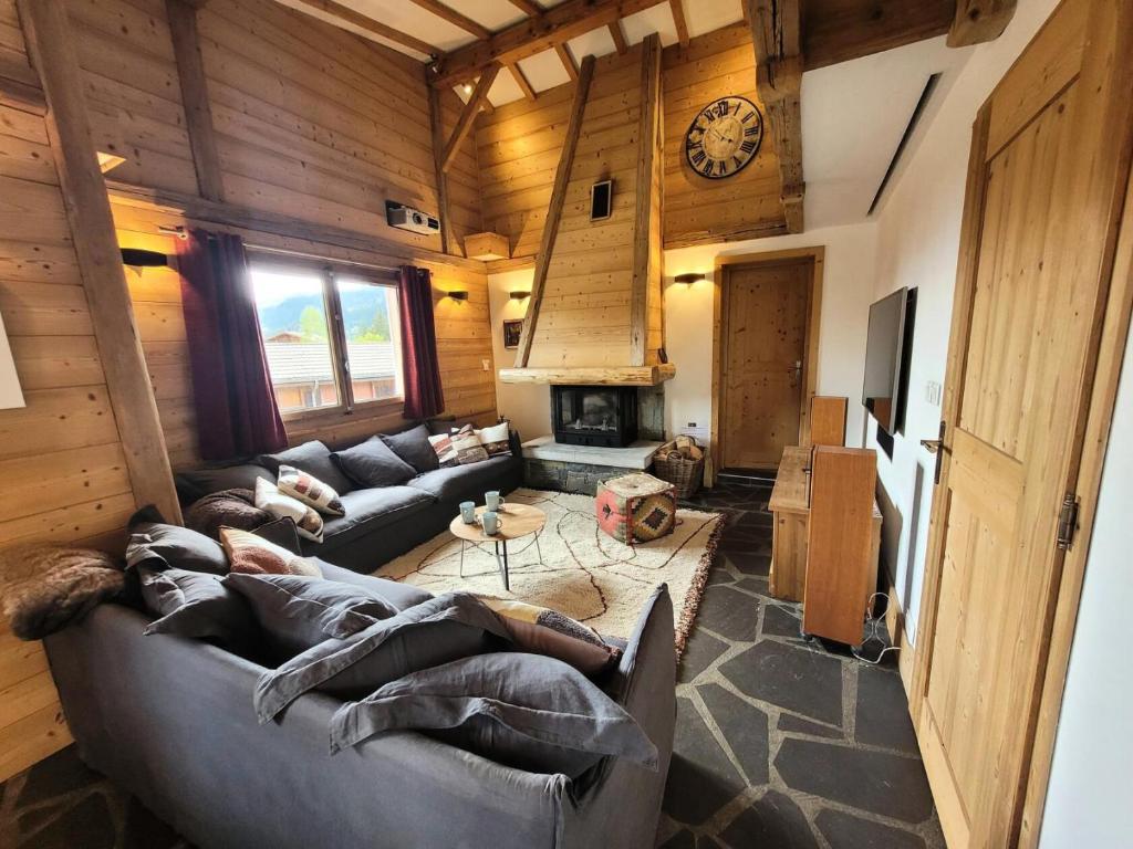 - un salon avec des canapés et une horloge murale dans l'établissement Chalet La SilÈne - Chalet de charme aux Chavannes avec vue et confort MAE-3411, aux Gets