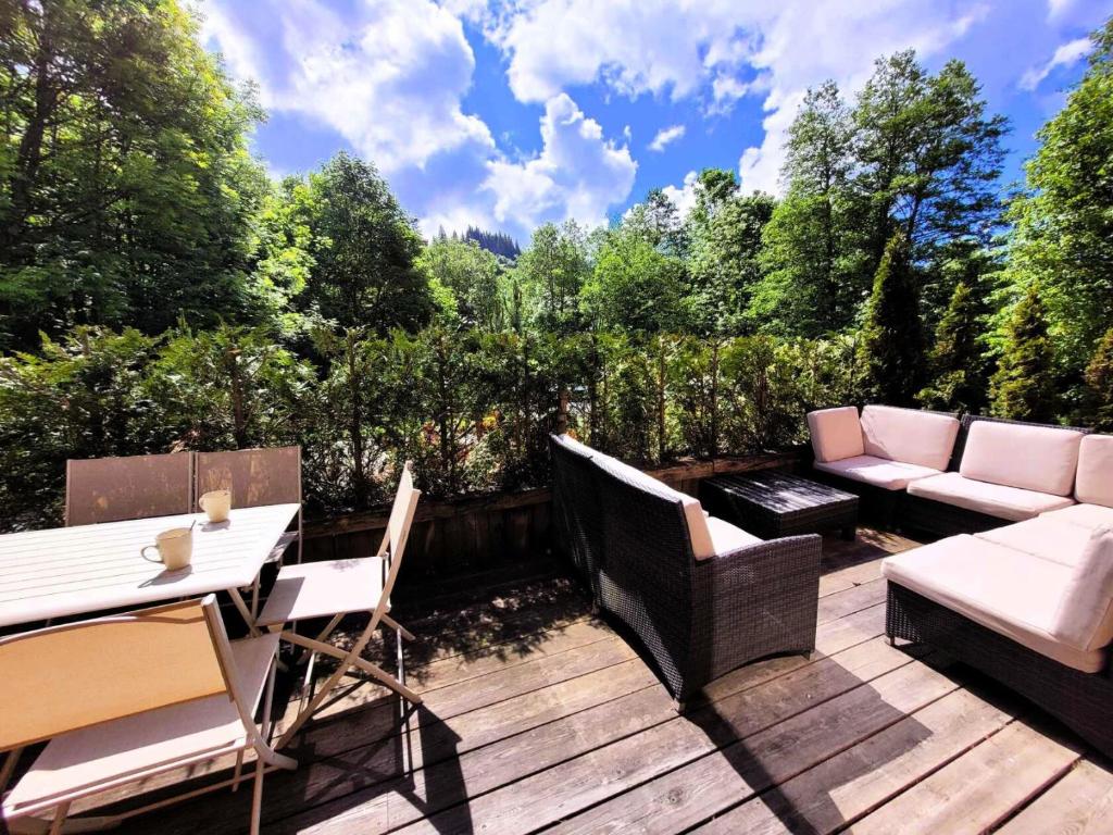 une terrasse en bois avec une table et des chaises. dans l'établissement Résidence Le ChampÉ - Grand appartement de plain-pied avec terrasse MAE-3421, aux Gets