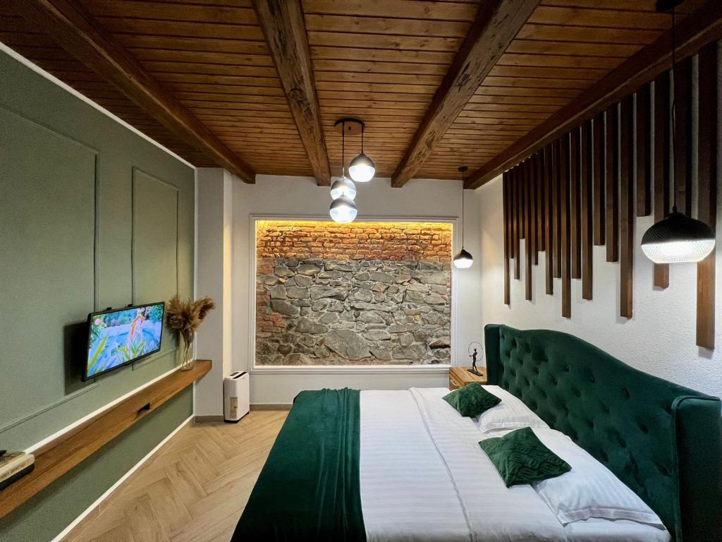 a bedroom with a green bed and a stone wall at Casa Ceauș in Baia-Sprie