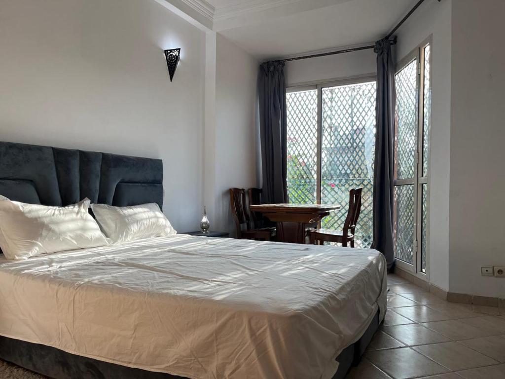 een slaapkamer met een bed, een tafel en ramen bij Perfect only family apartment & air cooling in Marrakesh