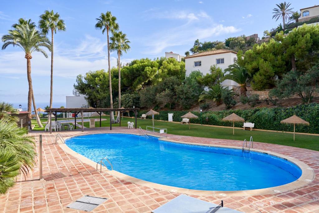 a swimming pool in a resort with palm trees at Apartamento Sol de la Molina in Salobreña