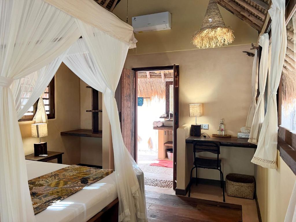 a bedroom with a bed and a desk and a window at Gili Asahan Eco Lodge & Restaurant in Gili Asahan