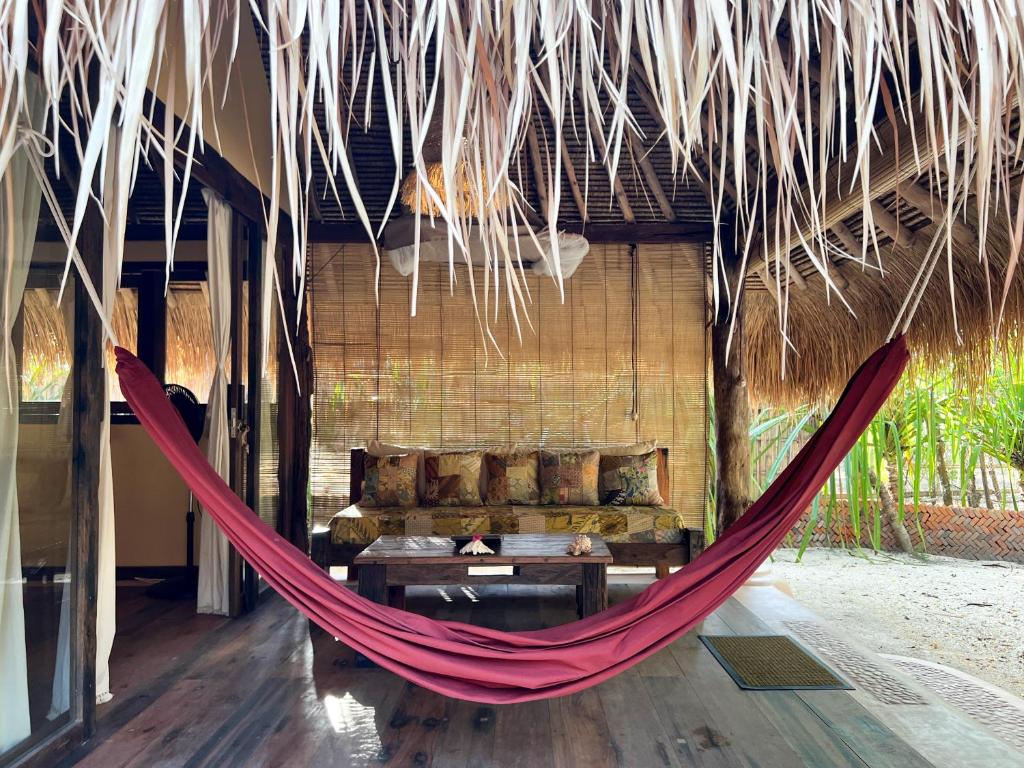 a hammock in a resort with a couch and a table at Gili Asahan Eco Lodge & Restaurant in Gili Asahan