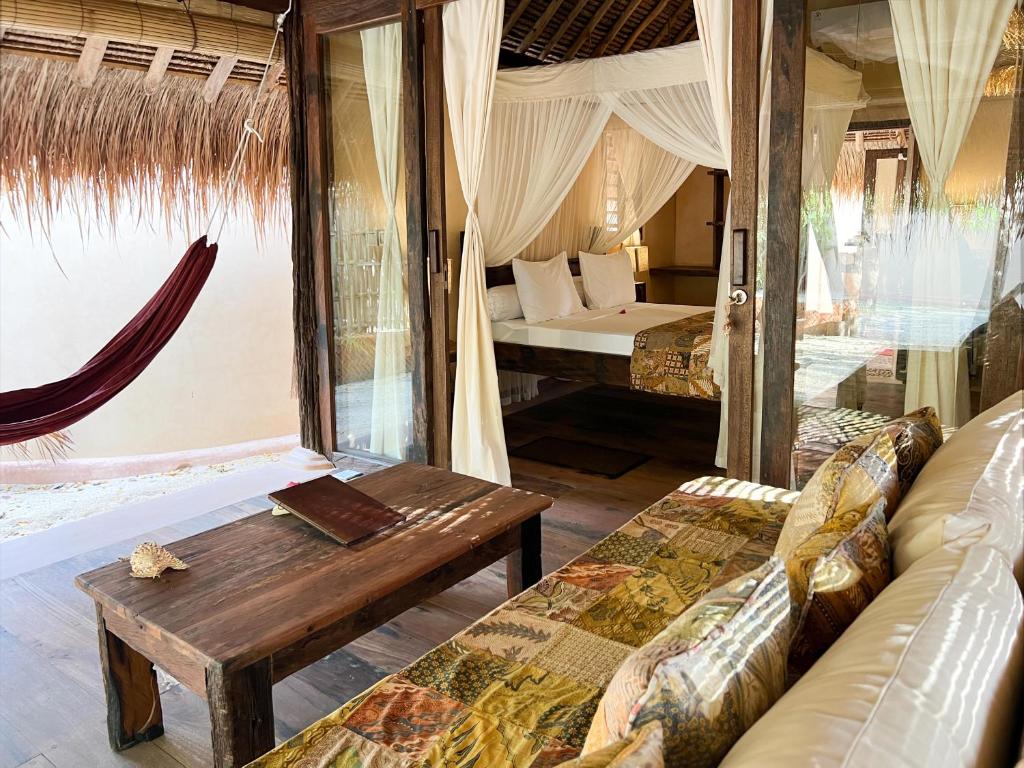 a room with a couch and a table and a bed at Gili Asahan Eco Lodge & Restaurant in Gili Asahan
