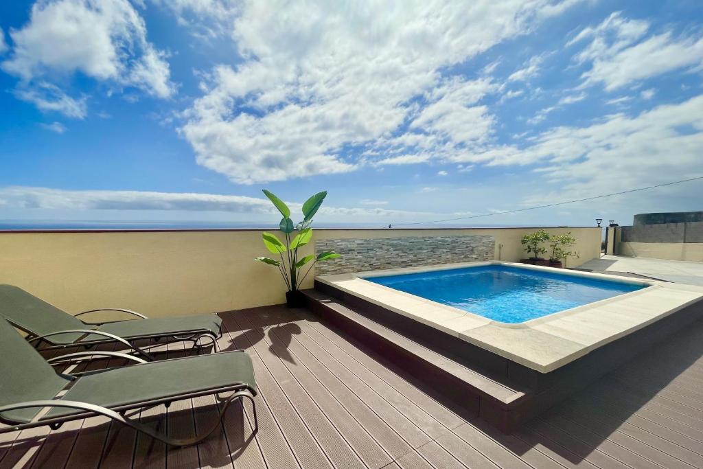 a swimming pool on a deck with chairs and the ocean at Casa Musiú: vistas únicas y excelente ubicación! in Las Nieves