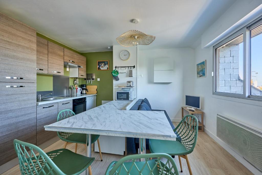 une cuisine et une salle à manger avec une table et des chaises dans l'établissement Les Jardins du Val Pican - Appt proche de la mer, à Courseulles-sur-Mer