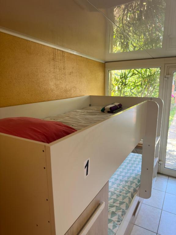 Cette chambre comprend un lit blanc et une grande fenêtre. dans l'établissement Agréable Dortoir en bord de jardin Lit 1, à Castres