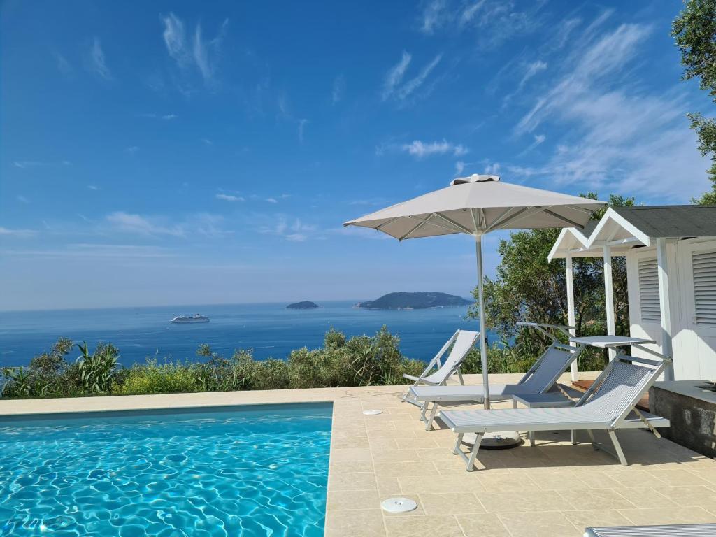 ein Swimmingpool mit zwei Stühlen und einem Sonnenschirm in der Unterkunft "Ulivi House" inside a Private Park, shared Pool, Tennis, 2 AC BDR, 2BTH, parking next home and private garage in Lerici! in Lerici