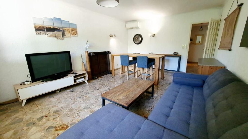 un soggiorno con un divano blu e un tavolo di Bas de villa avec piscine a Marsiglia