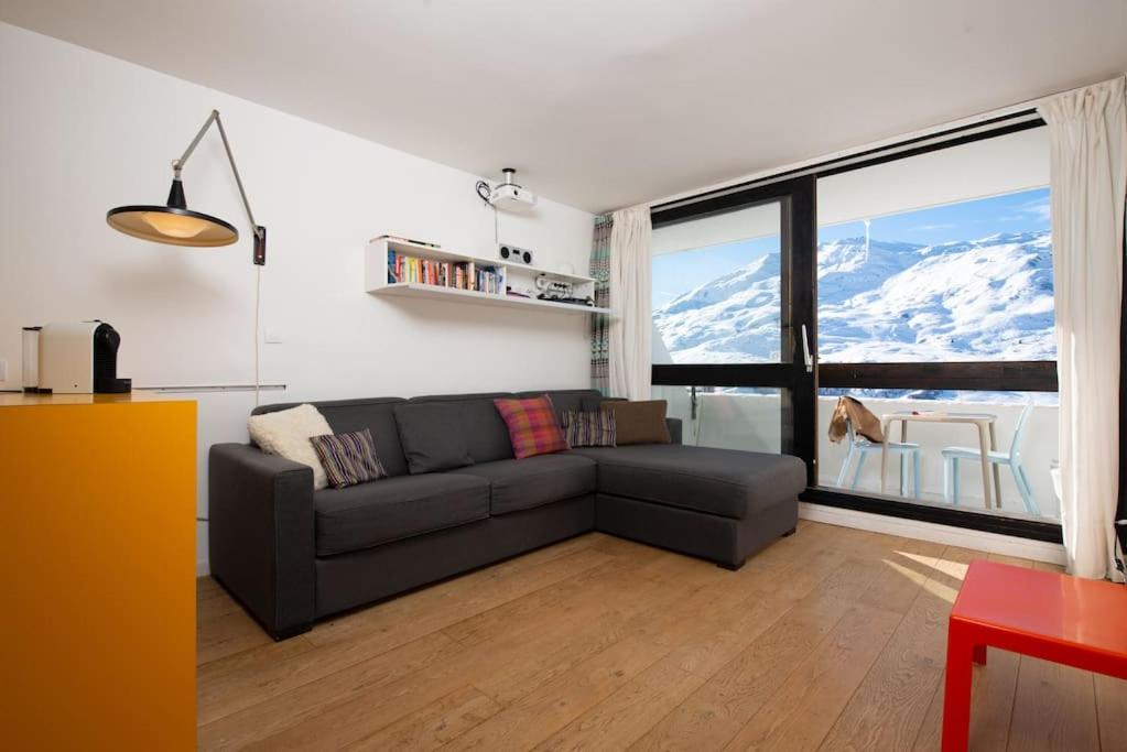un salon avec un canapé et une grande fenêtre dans l'établissement Ski in ski out with sought after location, aux Menuires
