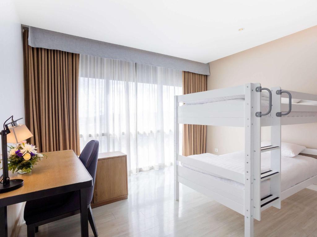 a bedroom with a desk and a bunk bed and a table and a deskablish at Novotel Phuket City Phokeethra in Phuket Town