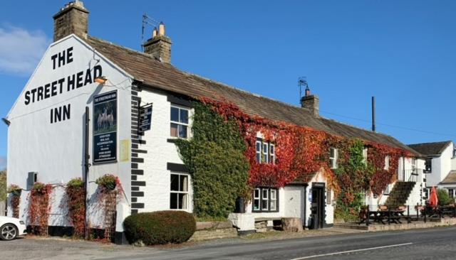 a white building with a sign on the side of it at The Street Head Inn in West Burton