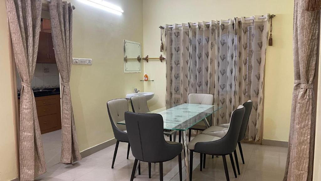 een eetkamer met een glazen tafel en stoelen bij Nisarga Jagannath Manor in Bellary