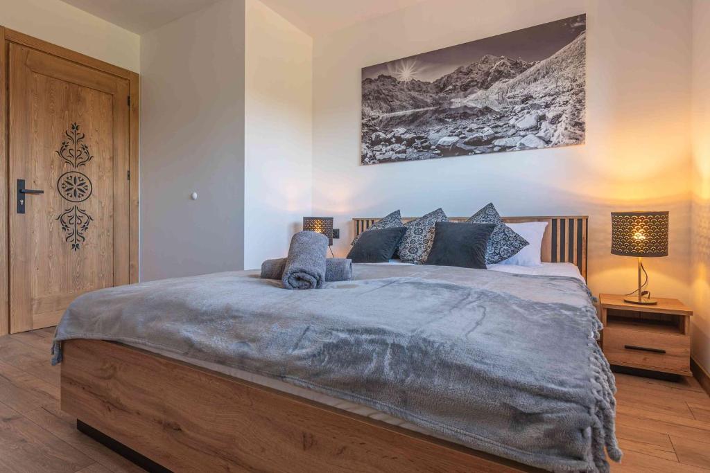 a bedroom with a large bed with blue pillows at Apartamenty Tatrzańskie Wzgórze in Poronin