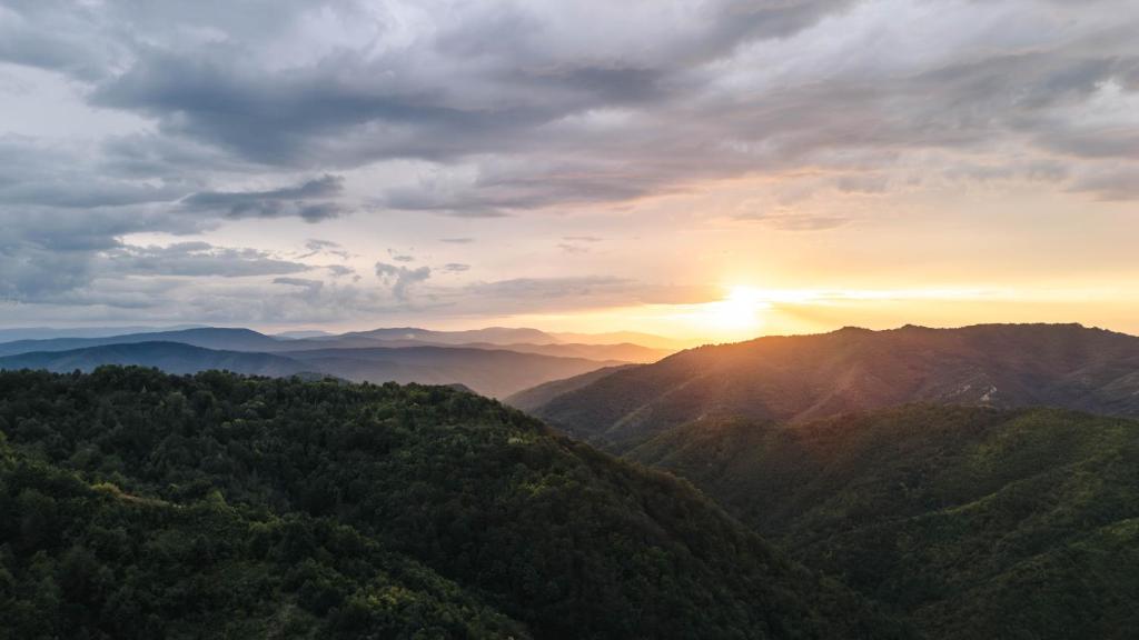 a sunset over a mountain range with the sun setting at Lodge Zeleni svet in Crni Vrh