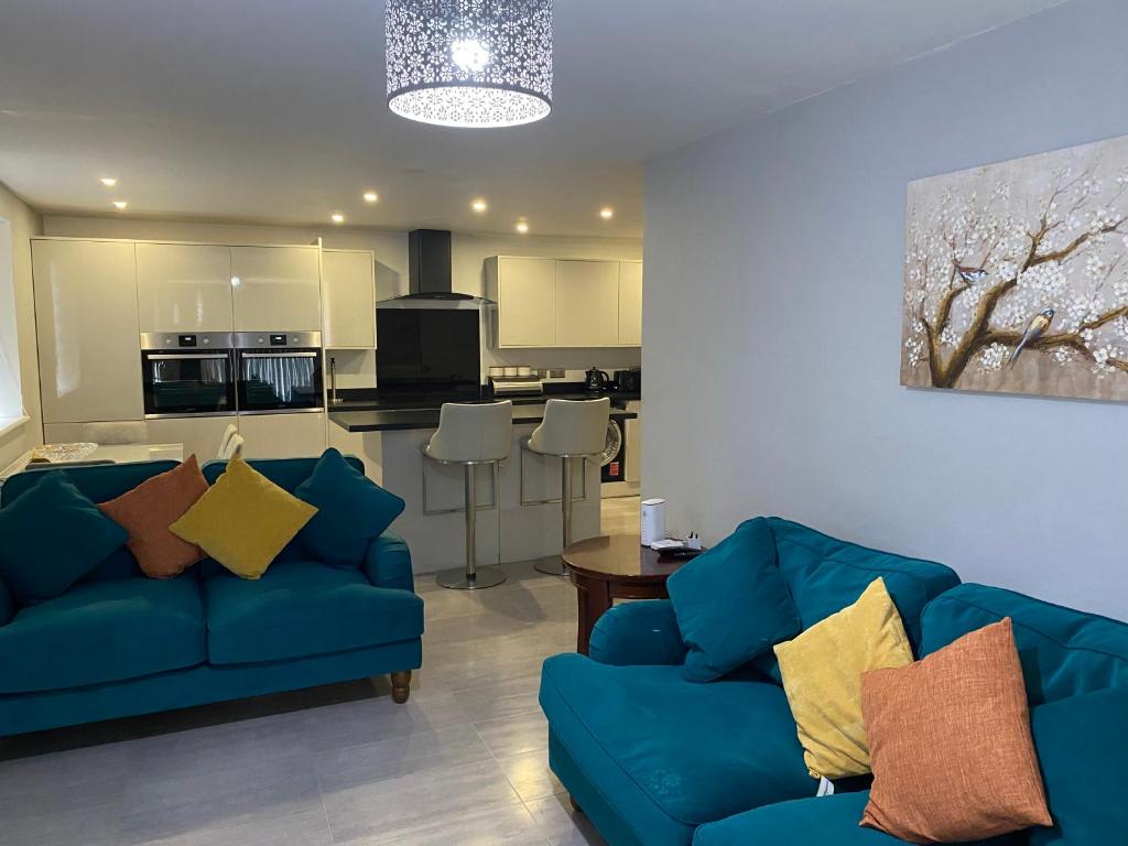 sala de estar con 2 sofás azules y cocina en Modern 2 bedroom flat with Sky TV & free parking, en Dagenham