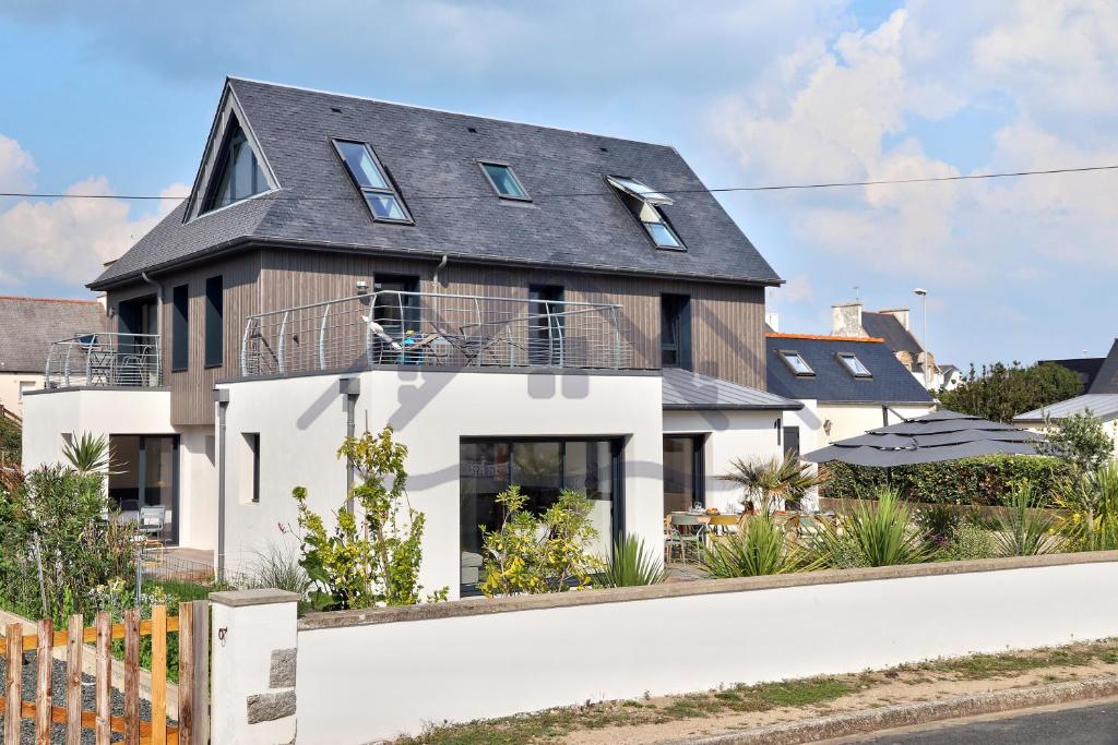 une maison avec un toit noir et une façade blanche dans l'établissement LocaLise - M14 - Caligourdaine - Maison d'exception - Construction de 2024 - à 30m de la mer et quelques pas des plages - extérieur clos - 4 places de parking privatives - wifi inclus - draps inclus - centre et port à 7 minutes à pied, au Guilvinec