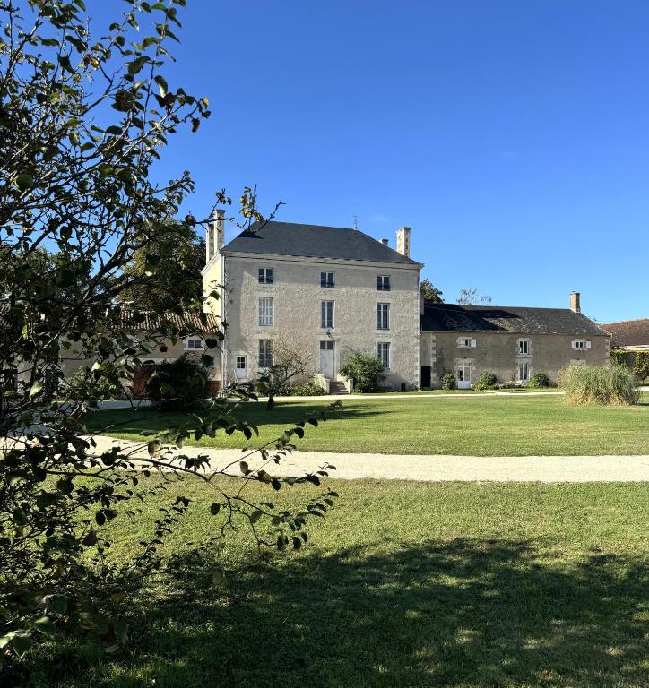 une grande maison blanche avec une cour gazonnée dans l'établissement Domaine la Boulinière - Le Sanglier, à Journet
