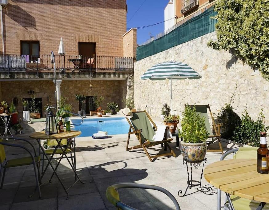 a patio with chairs and an umbrella and a pool at Casa Rural El Mirador de la Vega in Horche