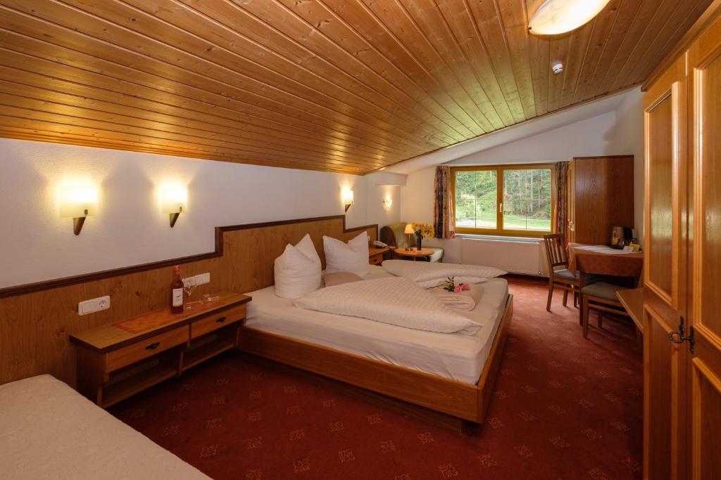 una camera con un grande letto e un soffitto in legno di Hotel Garni DIAS a Kappl