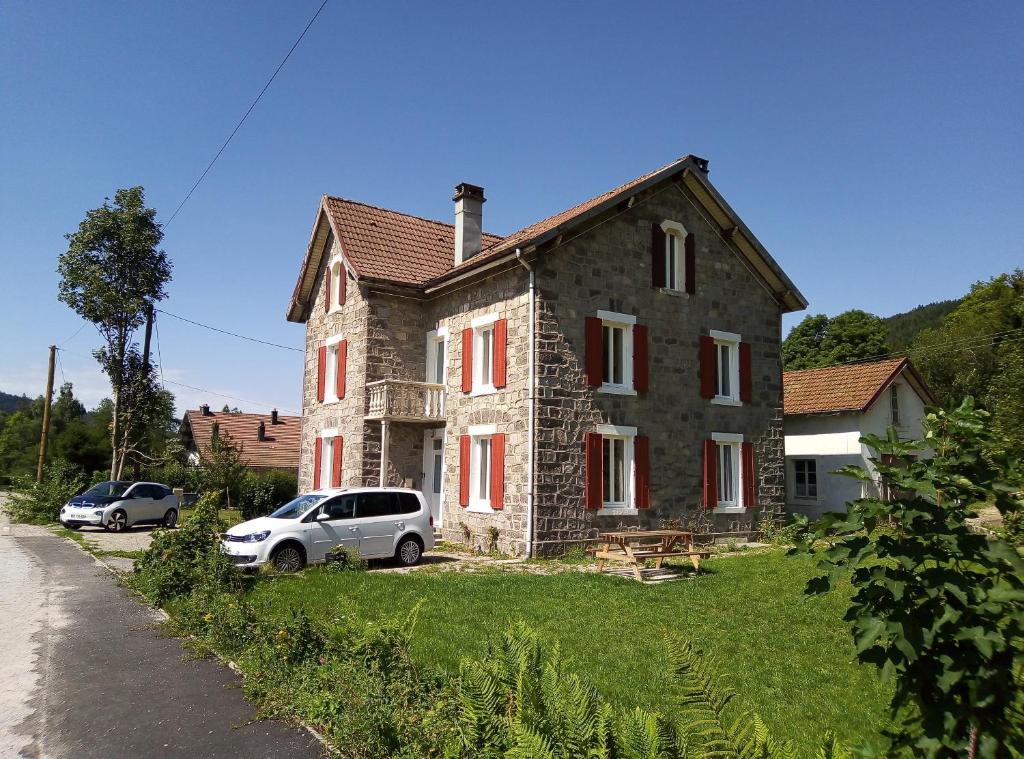 une maison avec deux voitures garées devant elle dans l'établissement Gite les Granites à moins de 100m du lac, à Gérardmer