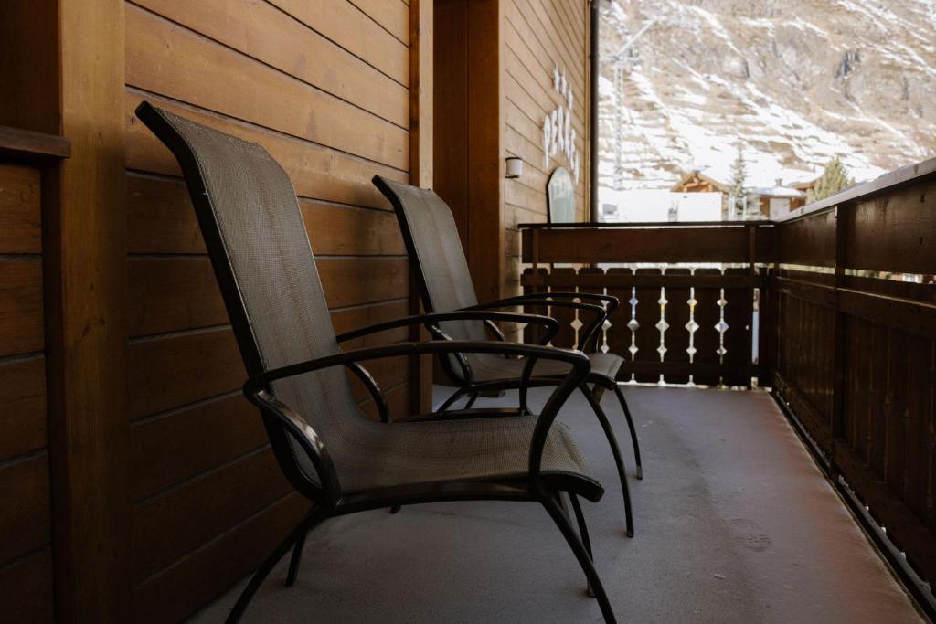 two chairs sitting on a porch with a snowy mountain at Alpine Hotel Perren in Zermatt