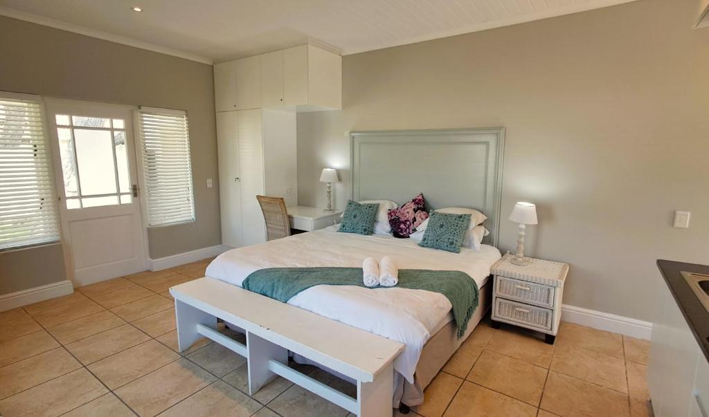 a bedroom with a large bed with a bench on it at The Dunes Studio 38 in Plettenberg Bay