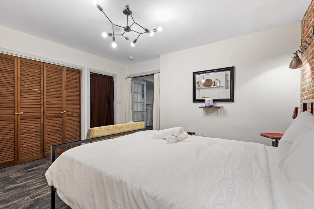 a bedroom with a white bed and a chair at Cheery Flat in Adams Morgan - Mt Pleasant in Washington, D.C.