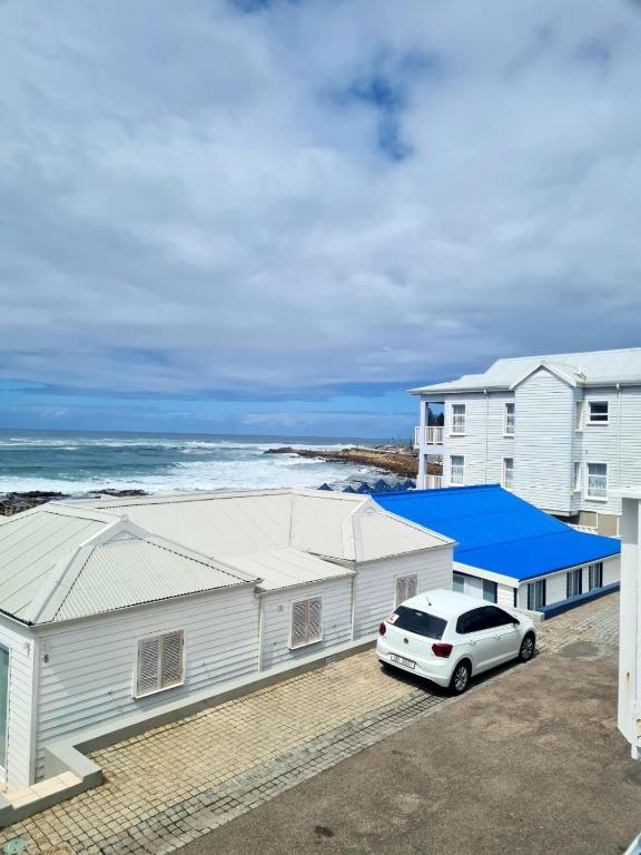 a white car parked in front of a building with the ocean at Point Village Accommodation -Linky's House in Mossel Bay