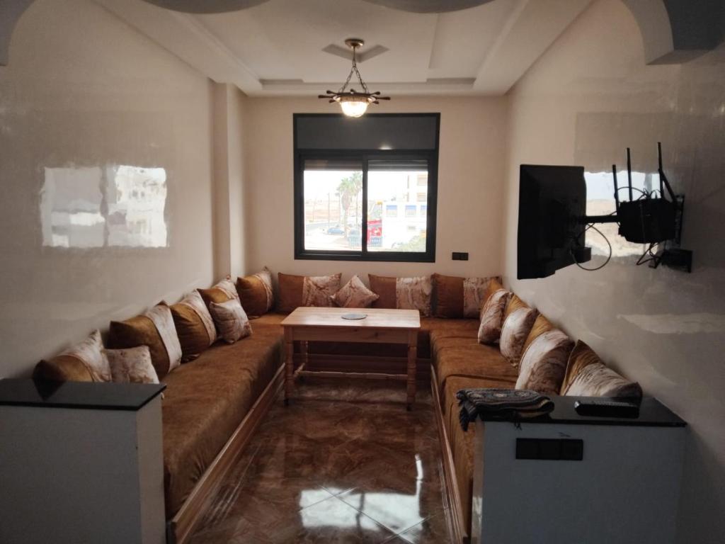 a living room with a large couch and a tv at Appartement familial 1 in Oualidia