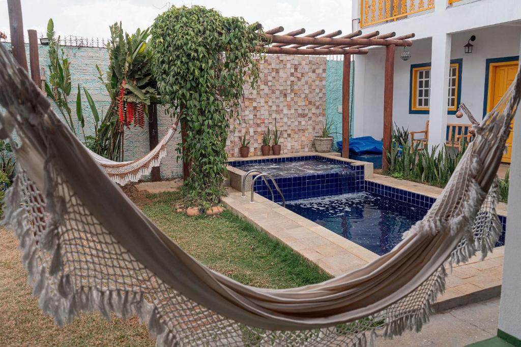 a hammock in front of a house with a pool at Cerrado 07 - Suítes individuais em pousada in Pirenópolis