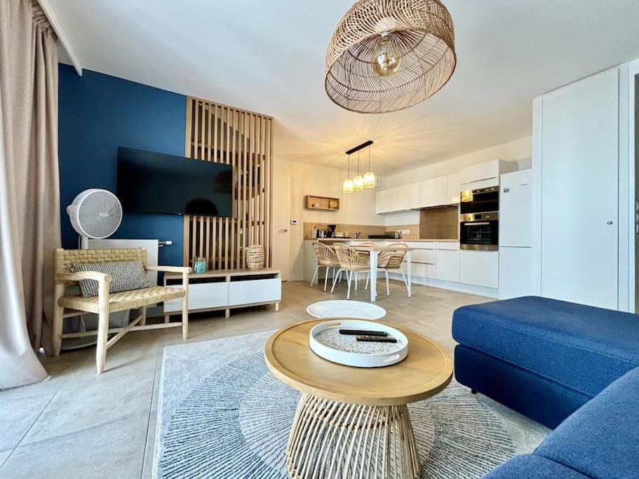 un salon avec un canapé bleu et une table dans l'établissement Appartement élégant hyper centre Arcachon plage classé 3 étoiles, à Arcachon