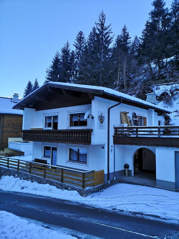 a white house with a balcony in the snow at Ferienchalet HOLDERNACH in Kappl