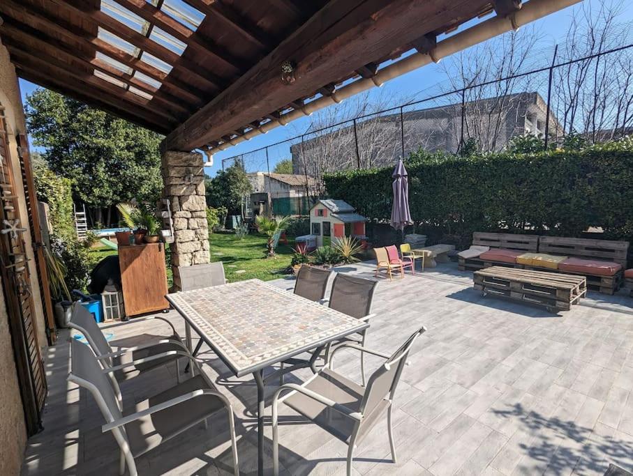 d'une terrasse avec une table, des chaises et un banc. dans l'établissement Maison cosy et jardin, à Avignon