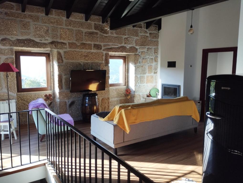 ein Wohnzimmer mit einem Bett und einem Fernseher in der Unterkunft Casa do Reguengo, Freigil in Resende