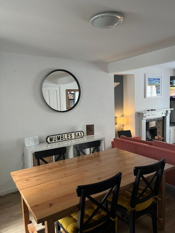 ein Esszimmer mit einem Holztisch und einem Spiegel in der Unterkunft Oysterman's Cottage in The Mumbles