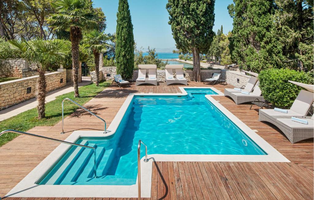 una piscina con sedie a sdraio accanto a una terrazza in legno di Pet Friendly Home In Supetar With House Sea View a Supetar (San Pietro di Brazza)