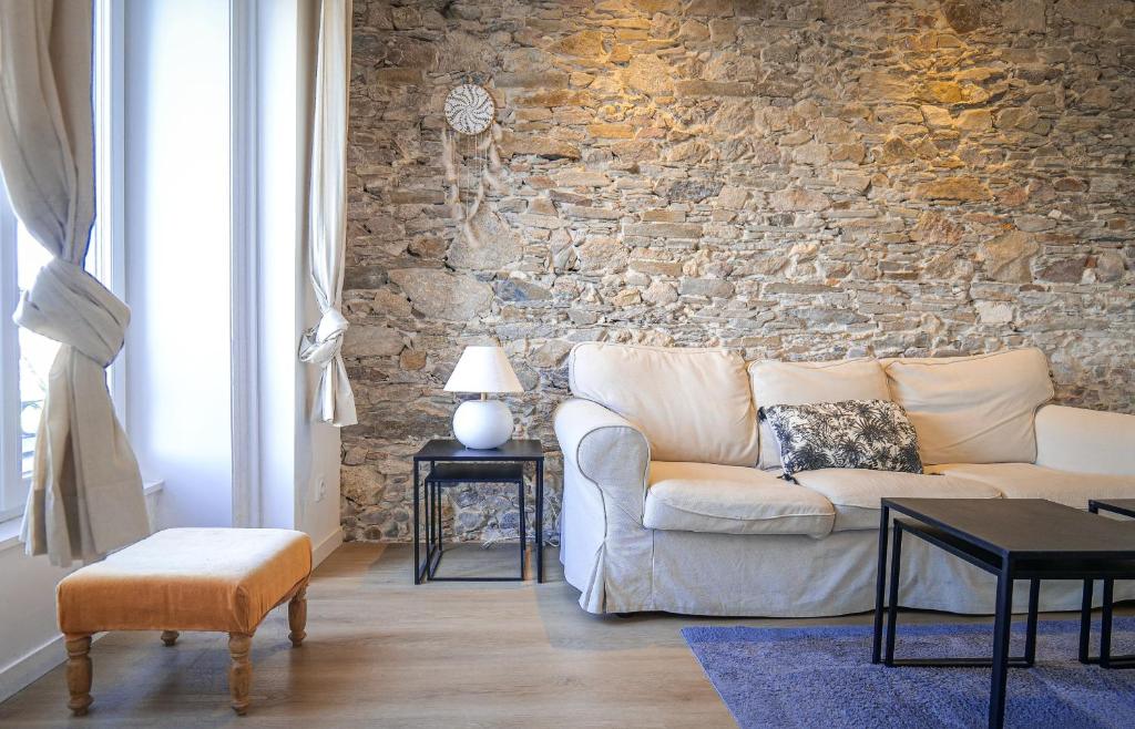 un salon avec un canapé et un mur en pierre dans l'établissement Joli appartement rénové sur le port de pêche avec une superbe vue sur le port des Sables - 4 personnes, à Les Sables-dʼOlonne