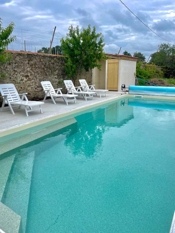 - une piscine avec des chaises blanches dans l'établissement L'Origami - Domaine de la Houblette, à Challans