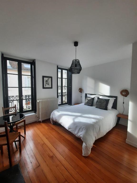 une chambre avec un grand lit blanc et du parquet dans l'établissement Maison Rinette, à Dijon