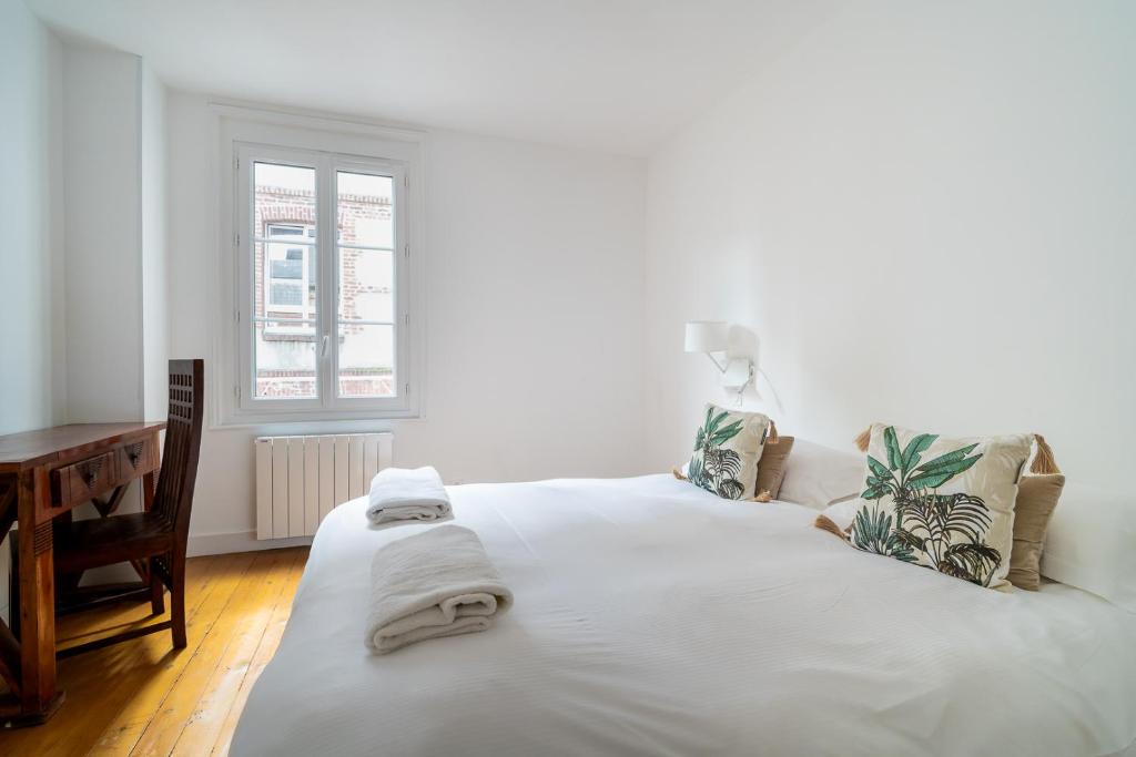 a bedroom with a large white bed with towels on it at Villa Arthur in Deauville