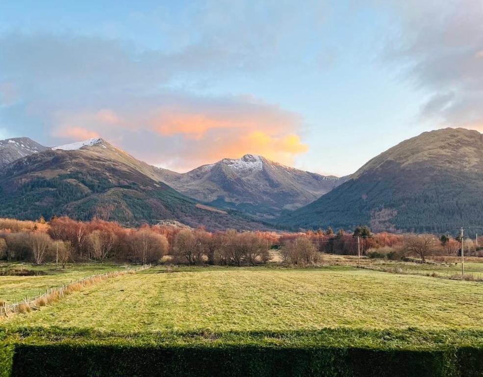 a field in front of a mountain range with mountains at View of the Mountain in North Ballachulish
