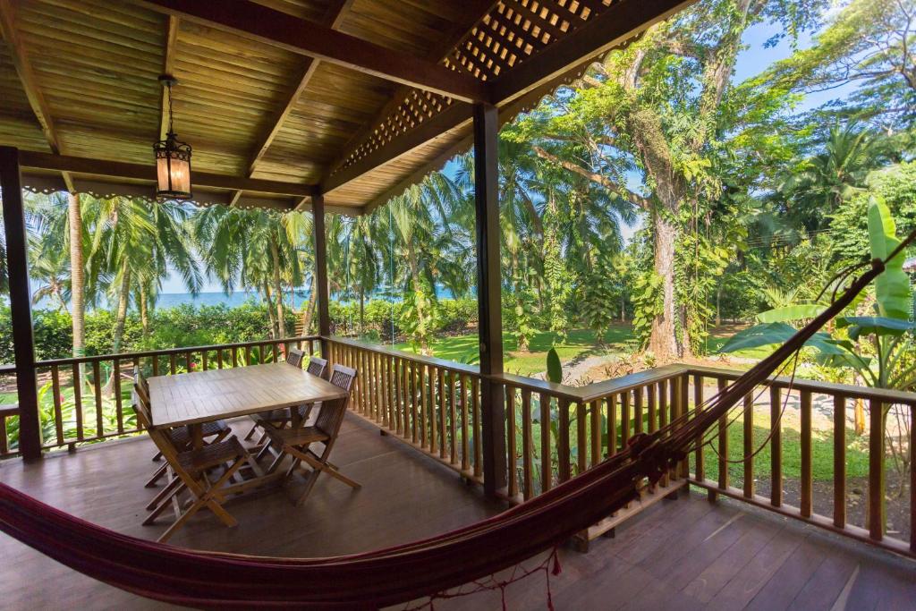 a hammock on a porch with a view of the ocean at Beachfront Villa Sea Breeze w AC and POOL in Puerto Viejo