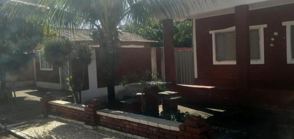 a house with a palm tree and a brick wall at Chalé jane in Caldas Novas