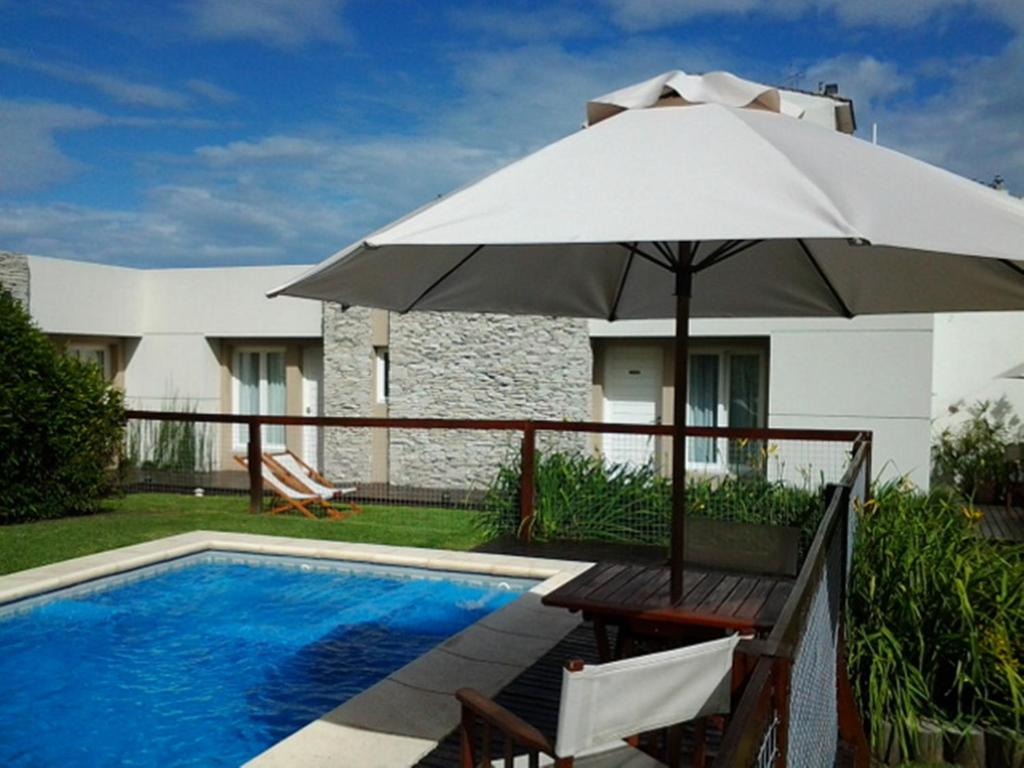 an umbrella and a bench next to a swimming pool at Villa Nuccia Hotel Boutique in Mar del Plata