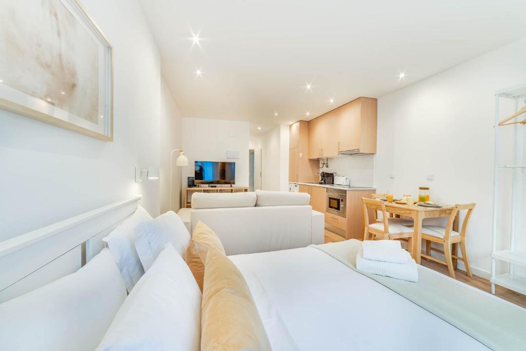 a living room with a white couch and a kitchen at Blue Charm - Campolide Apartments in Lisbon