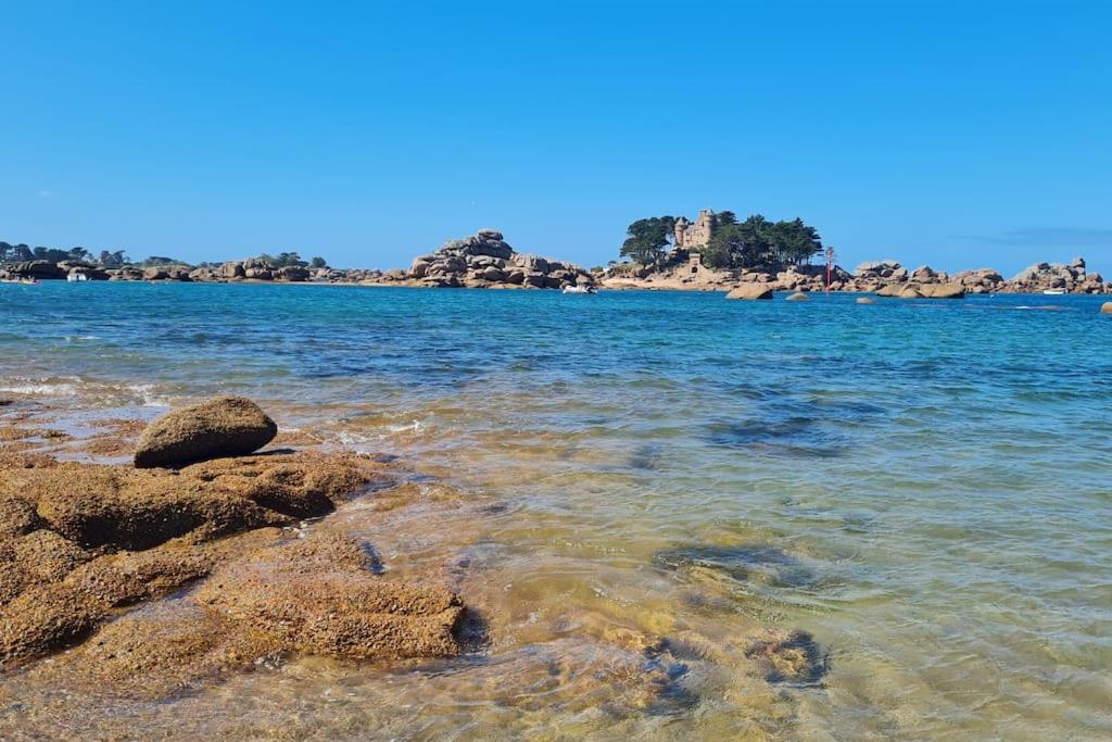 - une plage avec des rochers dans l'eau dans l'établissement Appartement Coeur de Granit Rose, à Perros-Guirec